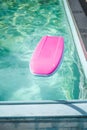 Pink float resting on the surface of a tranquil, blue swimming pool on a sunny day Royalty Free Stock Photo