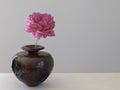 One stem of pink peony flower in a wooden vase on neutral background