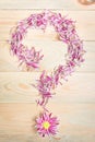 Pink flower petal arrange on wooden background as a question mar