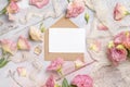 Pink flowers and a blank card with envelope laying on a marble table