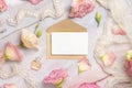 Pink flowers and a blank card with envelope laying on a marble table