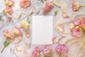 Pink flowers and a blank invitation card laying on a marble table