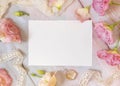 Pink flowers and a blank invitation card laying on a marble table