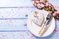 Pink flowers, heart, knife and fork on white plate on blue w