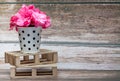 Pink flowers inside a white metal bucket with black polka dots on a wooden pallet. Wild flowers. Royalty Free Stock Photo