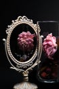 A pink flowers reflection in a Vintage Oval Desk Mirror with white frame on black background