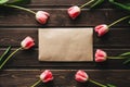 Pink flowers tulips with a paper postal envelope on a wooden table Royalty Free Stock Photo