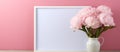Pink flowers in a vase beside a picture frame on a table Royalty Free Stock Photo