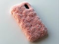 Pink fluffy phone case resting on white surface Royalty Free Stock Photo
