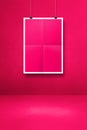 Pink folded poster hanging on a clean wall with clips