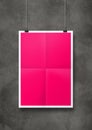 Pink folded poster hanging on a concrete wall with clips