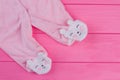 Pink footed baby pajama legs on wood.