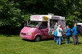 Pink Ford Transit van in a green park providing ice cream to customers in a queue Royalty Free Stock Photo