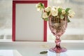 Pink frame mock up with sunlight and wineglass with white roses. Selective focus