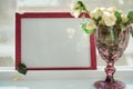 Pink frame mock up with sunlight and wineglass with white roses. Selective focus