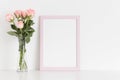 Pink frame mockup with a bouquet of pink roses in a glass vase on a white table. Portrait orientation Royalty Free Stock Photo