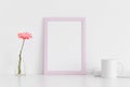 Pink frame mockup with a chrysanthemum in a vase, book and a mug on a white table. Portrait orientation Royalty Free Stock Photo
