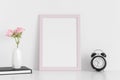 Pink frame mockup with workspace accessories  and pink roses in a vase on a white table.Portrait orientation Royalty Free Stock Photo