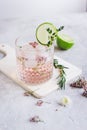 Pink fresh cocktail with flowers and cut lime on stone desk background Royalty Free Stock Photo