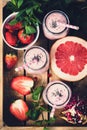 Pink fresh smoothies with grapefruit, strawberry and pomegranate in wooden tray, top view, selective focus, toned image Royalty Free Stock Photo