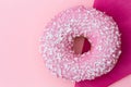 Pink frosted donut sprinkled with crystal sugar isolated on pink background and dark pink paper napkin from above. Space for text.