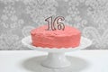 Pink frosted layer cake with the number 16 on top Royalty Free Stock Photo