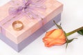 Pink gift box with bow and golden ring and orange rose Royalty Free Stock Photo