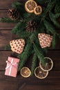 Pink gift box with cones, spruce branches, cookies shaped christmas tree and dry slices of citrus on a dark wooden background. Royalty Free Stock Photo