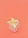 Pink gift box on coral color background, vertical.