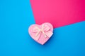 Pink gift box in the form of a heart with a bow on a blue background, top view Royalty Free Stock Photo