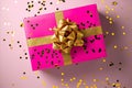 Pink gift box with a golden bow and confetti on a soft background Royalty Free Stock Photo