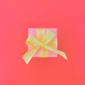 Pink gift box on an orangish red background. square.