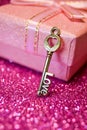 Pink gift box with ribbon bow and golden love key in the foreground on abstract glitter bokeh Royalty Free Stock Photo