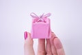 Pink gift box with ribbon for decorations in hand. Festive gift to a girl or woman