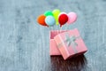 Pink gift box with silver ribbon and colorful balloon on wooden background. minimal hollyday concept