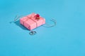 Pink gift box with thin tied rope with shadow on blue background Royalty Free Stock Photo