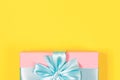 Pink gift box tied with blue ribbon with bow at the top on yellow background. Copy space for text. Minimal flat lay. Top view. Royalty Free Stock Photo