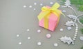 A pink gift box on grey background with gemstone and Oriental arborvitae branches.