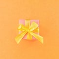 Pink gift box on orange color background. square.