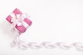 Pink gift box, white bow, long curved ribbon and empty space for text on white background.