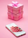 Pink gift boxes stacked above a smartphone with pink flowers Royalty Free Stock Photo
