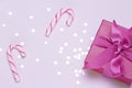 Pink gift with candy cane and silver confetti. Copy space for advertising. Concept to celebrate and to congratulate