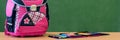 Pink girly school bag and pencil case on a desk against greenboard. First day of school. Royalty Free Stock Photo