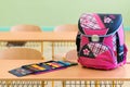 Pink girly school bag and pencil case on a desk in an empty classroom. First day of school. Royalty Free Stock Photo