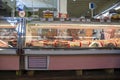 A pink glass freezer filled with raw chicken and beef and people standing behind the counter at the Municipal Market in Atlanta