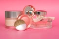 Pink glass perfume bottle, facial cream and some cosmetic and makeup products on pink background. Bottle of female