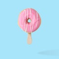 Pink glazed donut with ice cream stick on blue pastel background