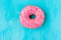 Pink glazed doughnut with sugar sprinkles on light blue background, in the middle, copyspace, template, birthday, card, poste