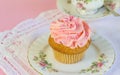 Pink glitter and pearl frosted cup cake on plate with teacup in Royalty Free Stock Photo