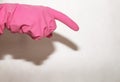 The pink glove dressed on a hand shows an index finger down on a white Royalty Free Stock Photo